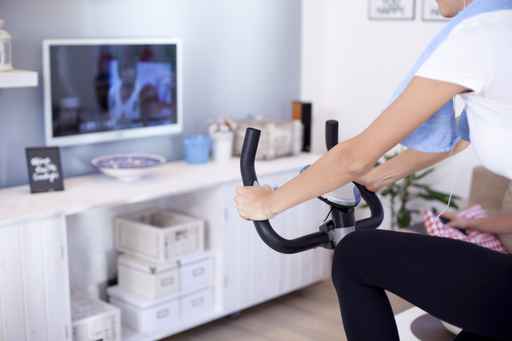 Sporty woman training on exercise bike in the living room,close