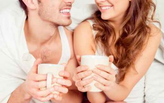 Cute young couple sitting together with cups and smiling