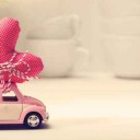 Miniature pink car carrying red heart cushion